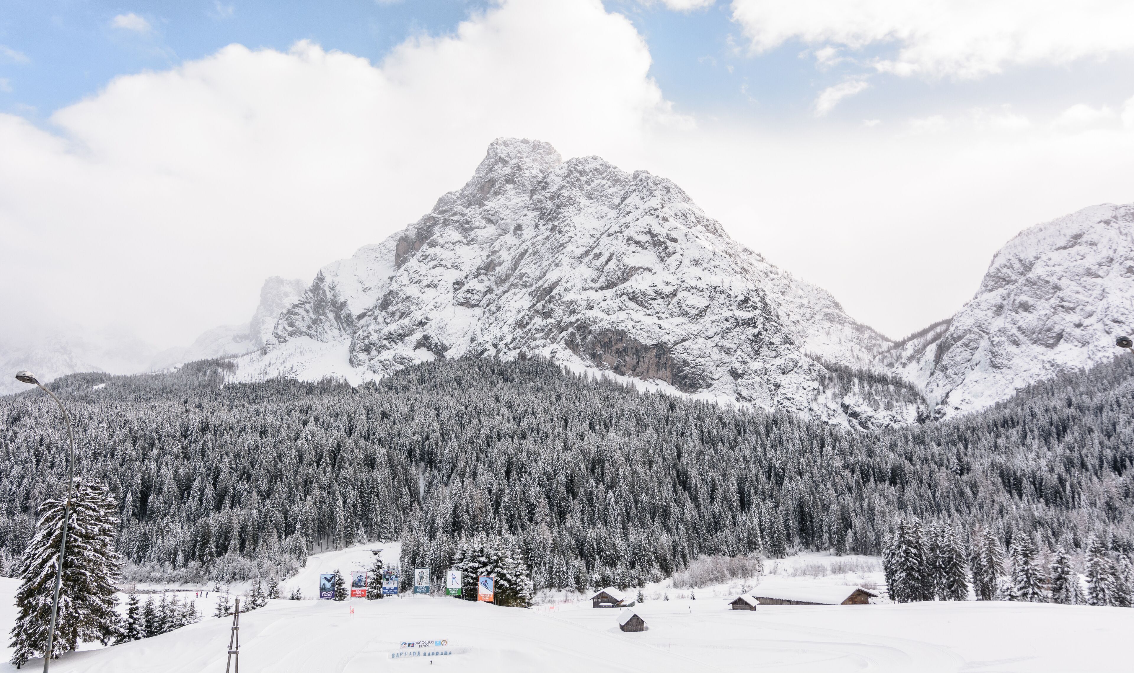 A snow-covered mountain range with dense forests and wooden cabins.