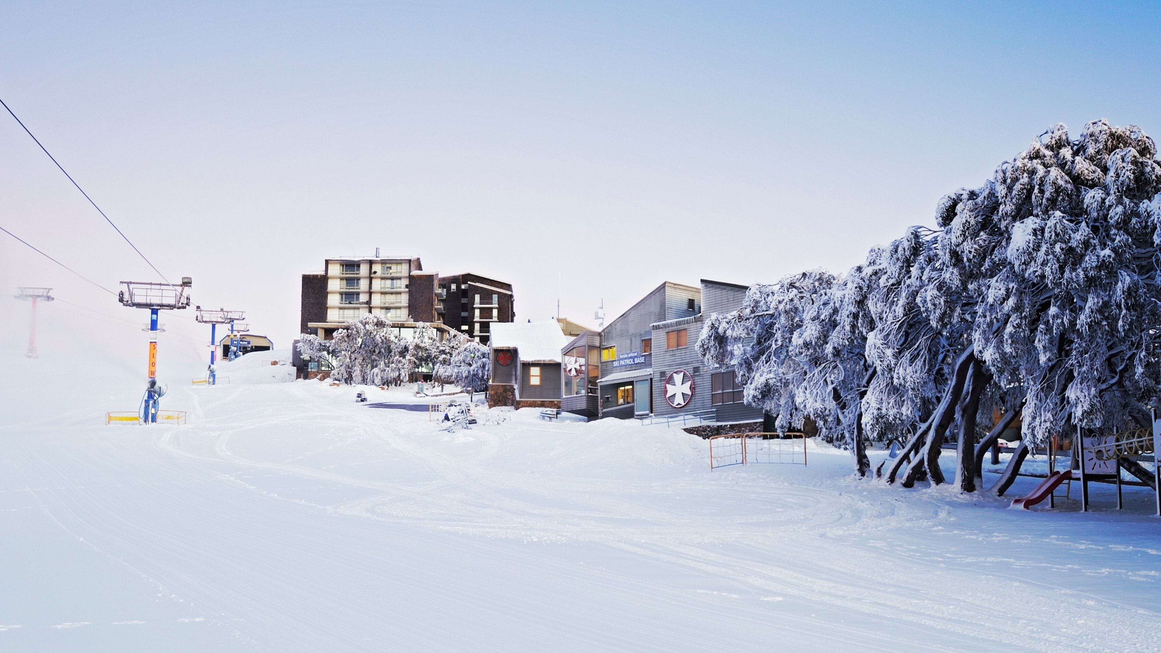A snowy ski resort with buildings, a ski patrol base, and a ski lift.