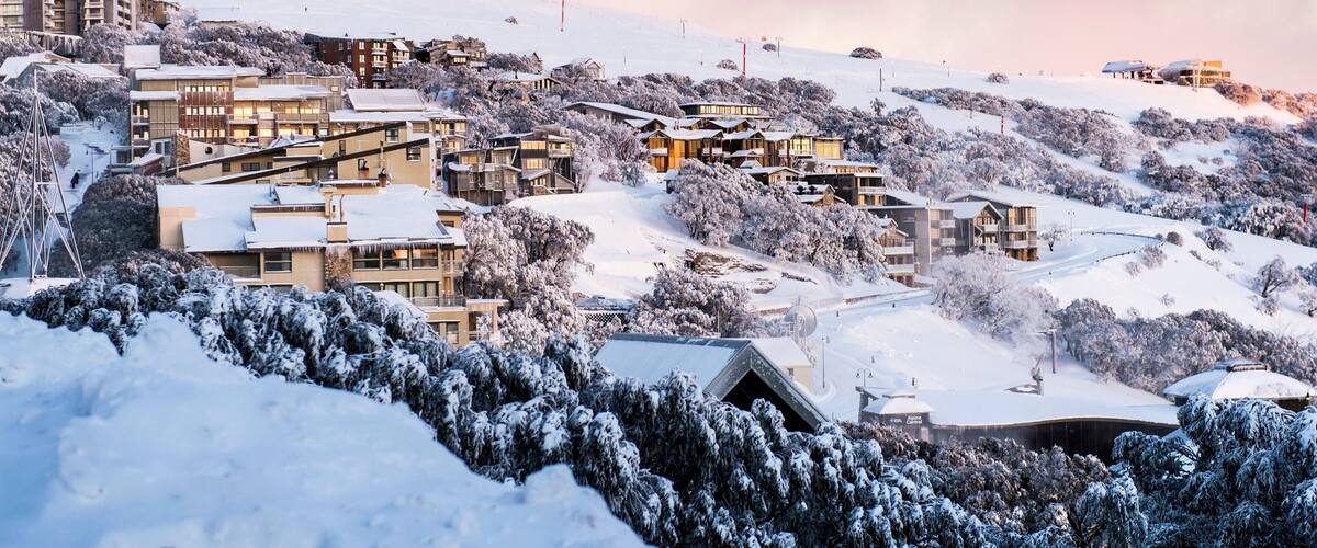 A snow-covered mountainous village with buildings and trees.