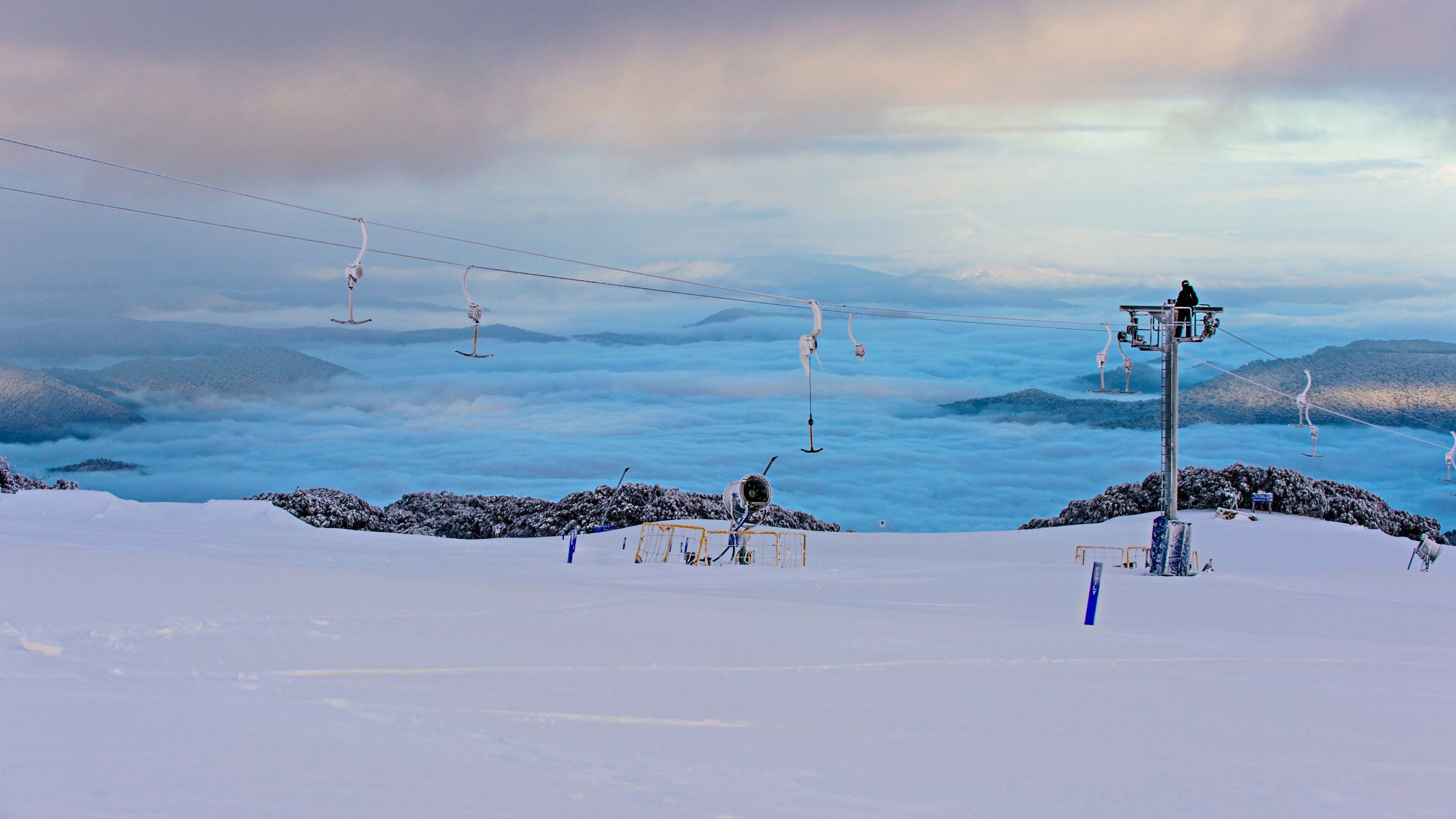 A snowy mountain landscape with ski lifts and a clear sky.
