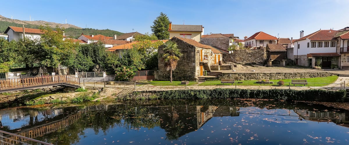 A riverside town with stone buildings, a bridge, and a small pond.