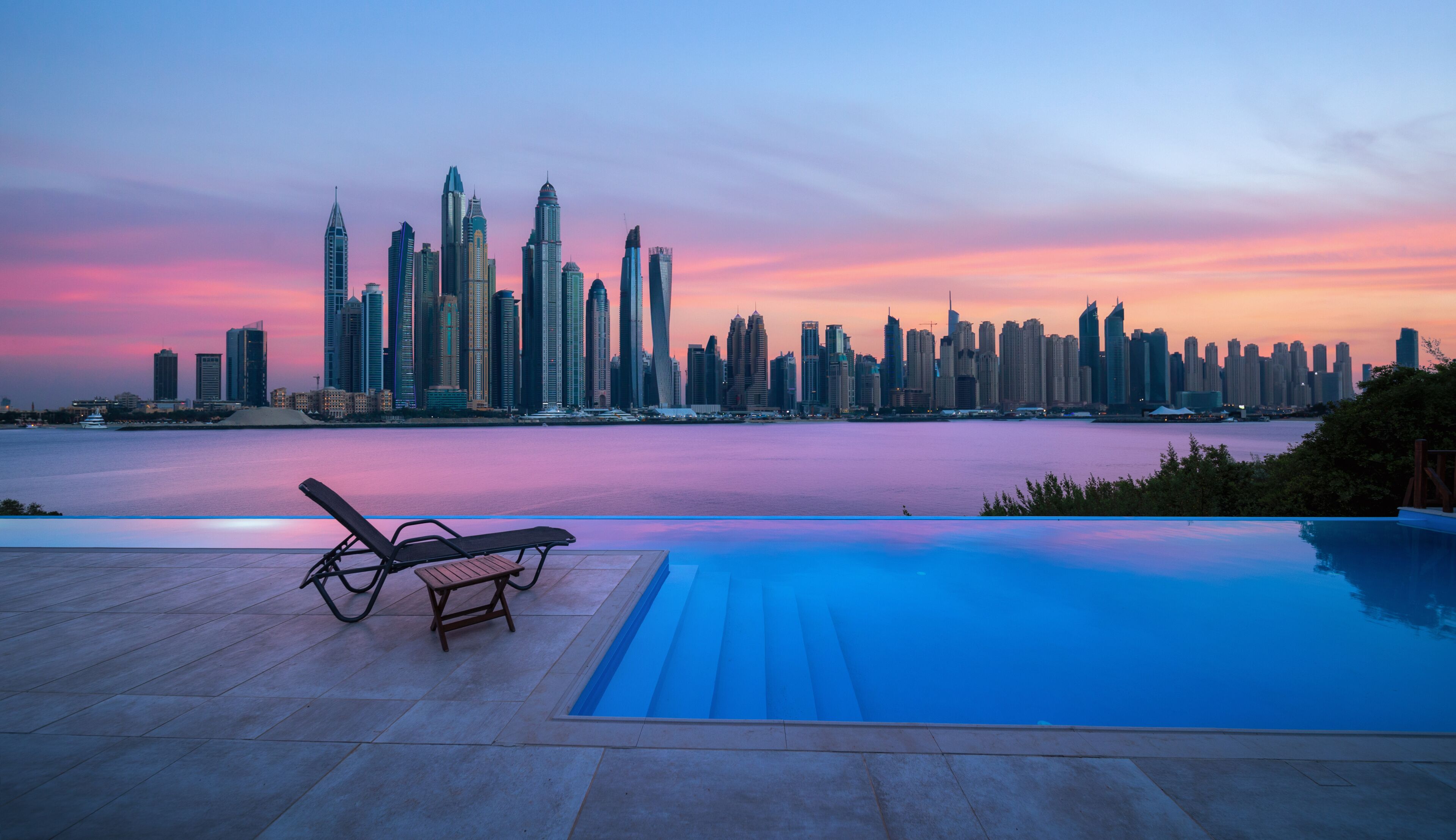 Skyline of Dubai Marina at a beautiful sunset with an infinity pool in front