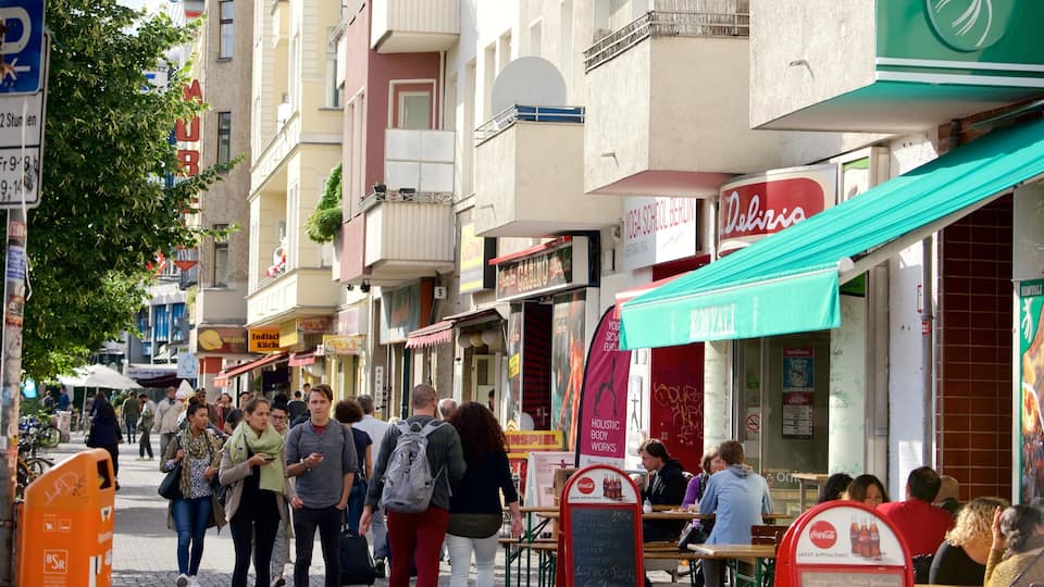 Une rue animée, avec des passants, des boutiques et un auvent vert.