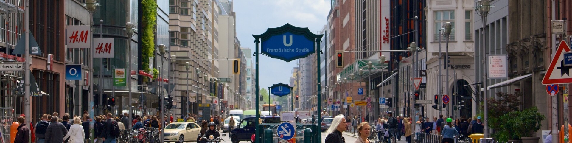A busy urban street with pedestrians, cyclists, and vehicles.