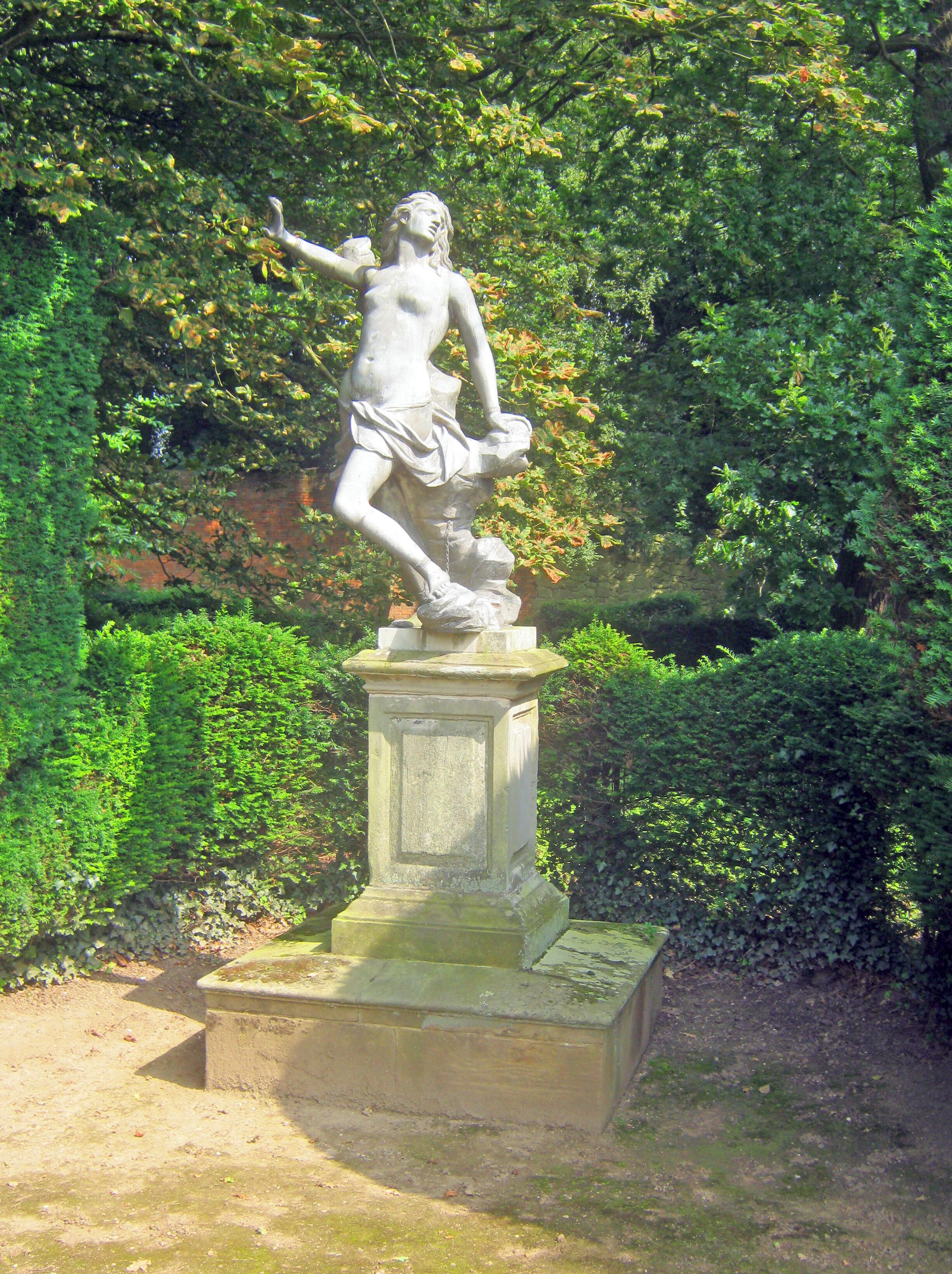 Una estatua clásica de una mujer en un jardín.