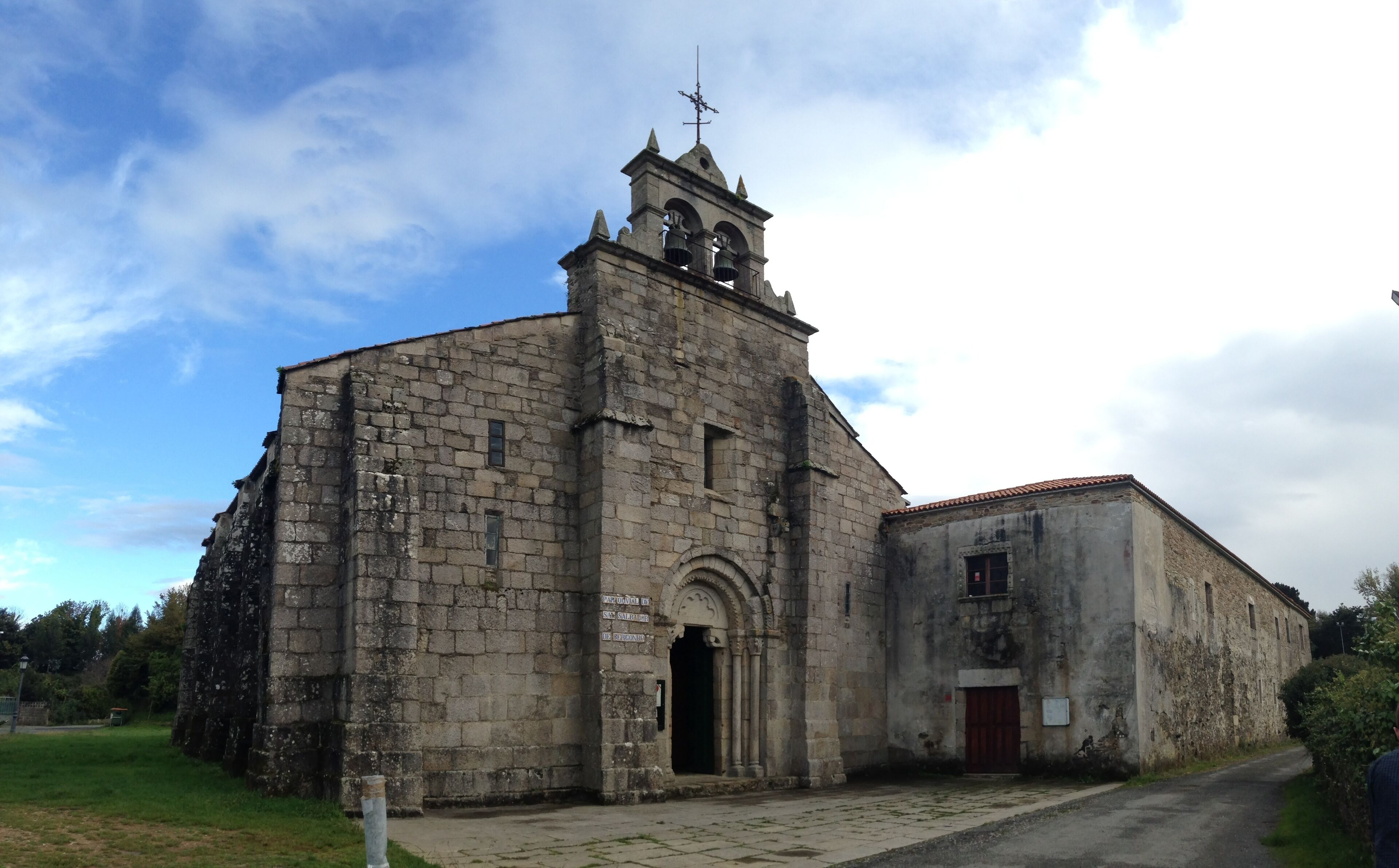 An old stone church with a bell tower and a smaller attached building.