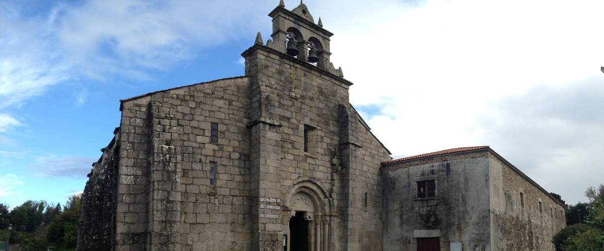 An old stone church with a bell tower and a smaller attached building.