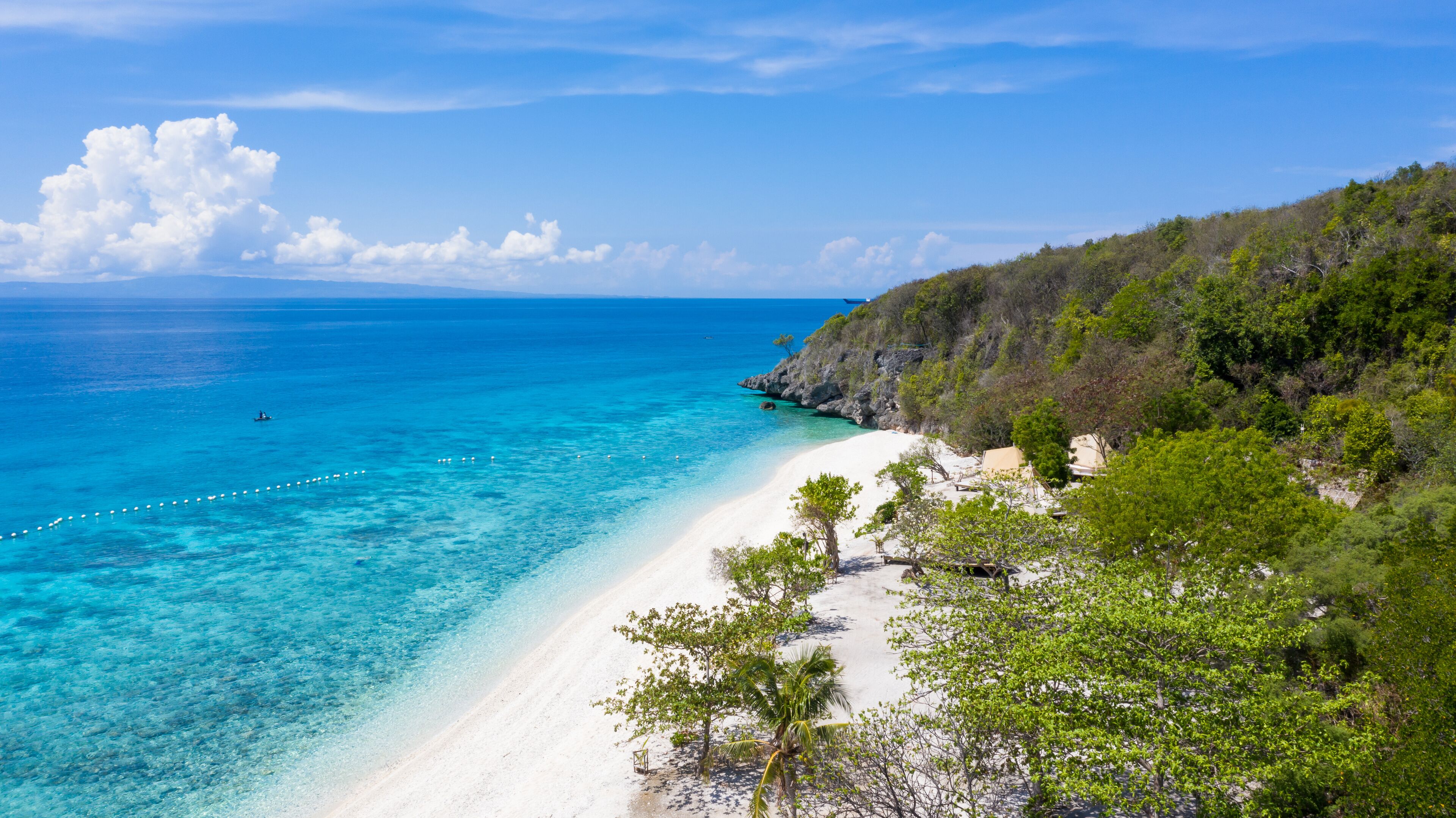 Aerial view of the Sumilon island, sandy beach with tourists swimming in beautiful clear sea water of the Sumilon island beach, Oslob, Cebu, Philippines.