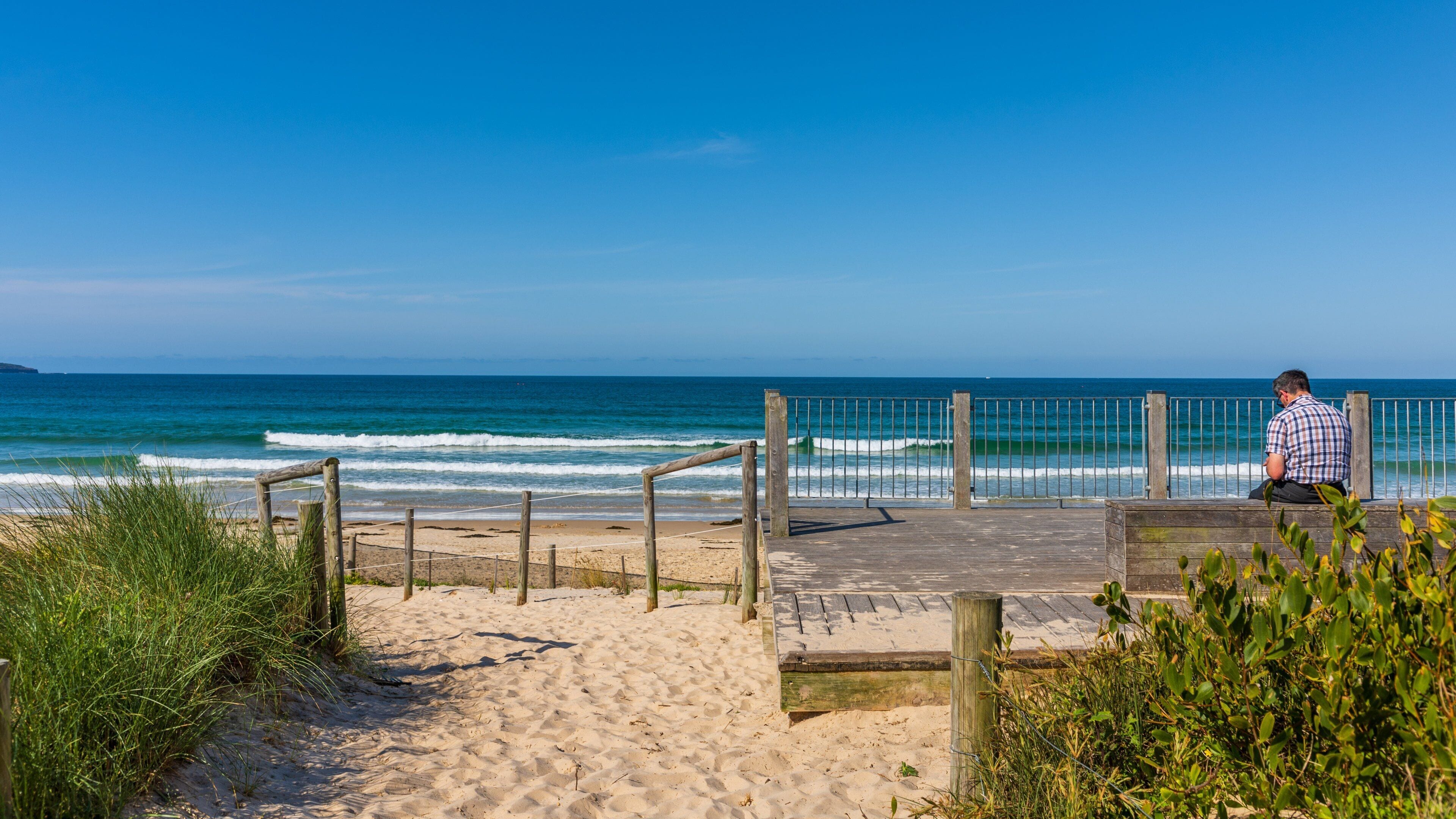A wooden boardwalk leading to a beach with waves crashing onto the shore.