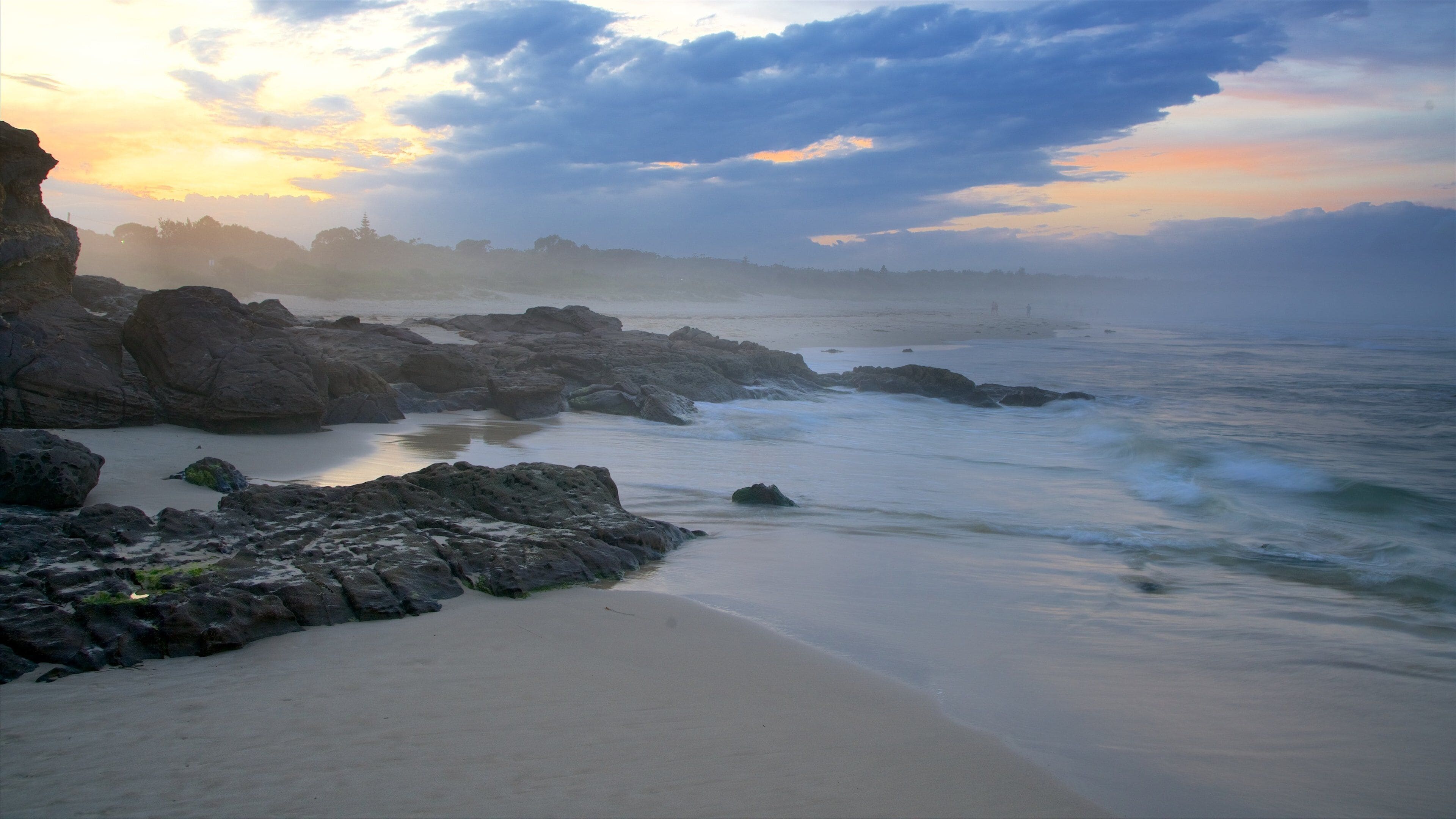 Una costa rocosa con olas al atardecer.