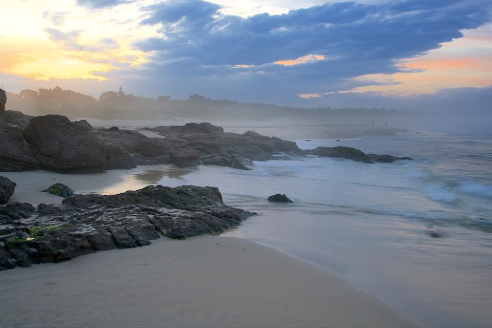 Una costa rocosa con olas al atardecer.