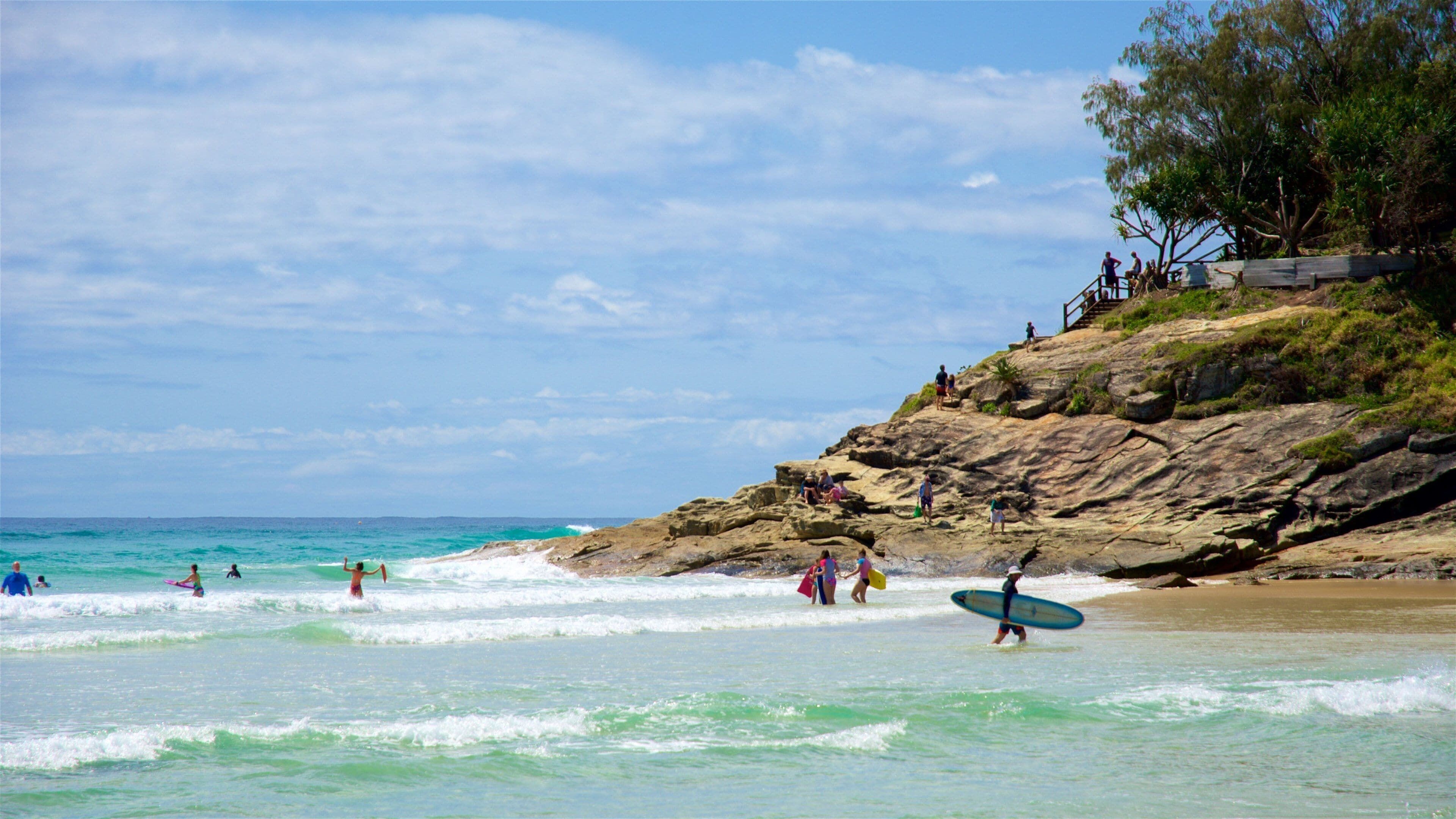 A beach with people surfing and walking along the shore.