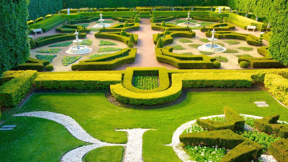A meticulously landscaped garden with geometric hedges, central fountains, and a symmetrical layout.