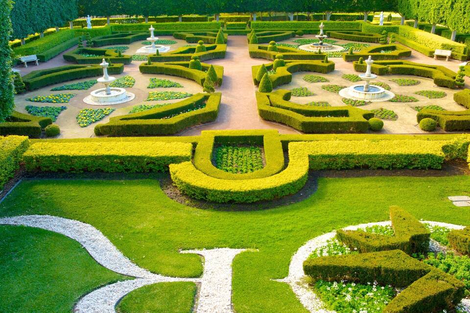 A meticulously landscaped garden with geometric hedges, central fountains, and a symmetrical layout.