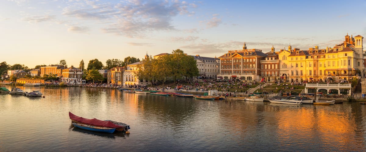 A riverside cityscape with historic buildings, a bridge, and boats.