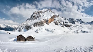 A snow-covered mountain with a wooden cabin in the foreground.