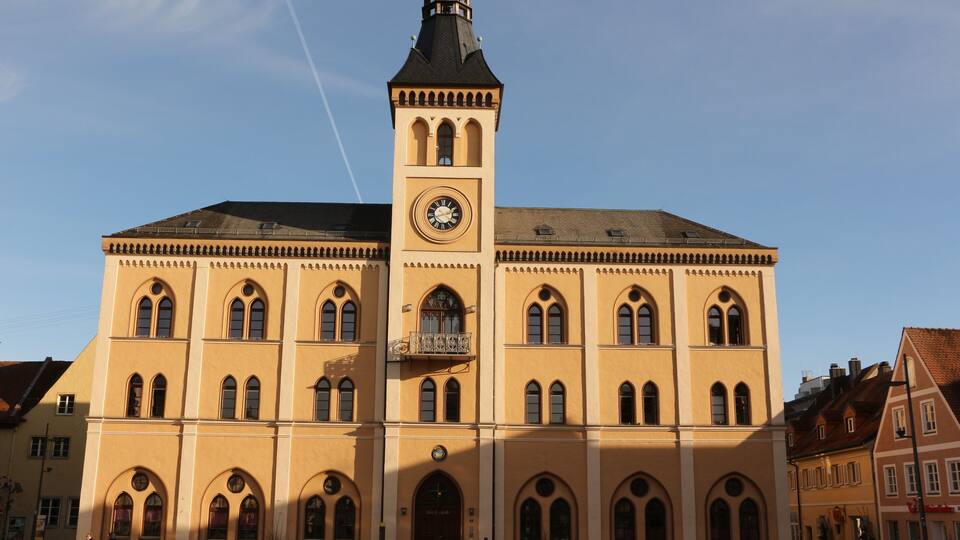 A large yellow building with a clock tower and arched windows.