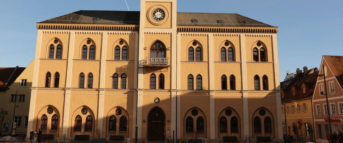 A large yellow building with a clock tower and arched windows.