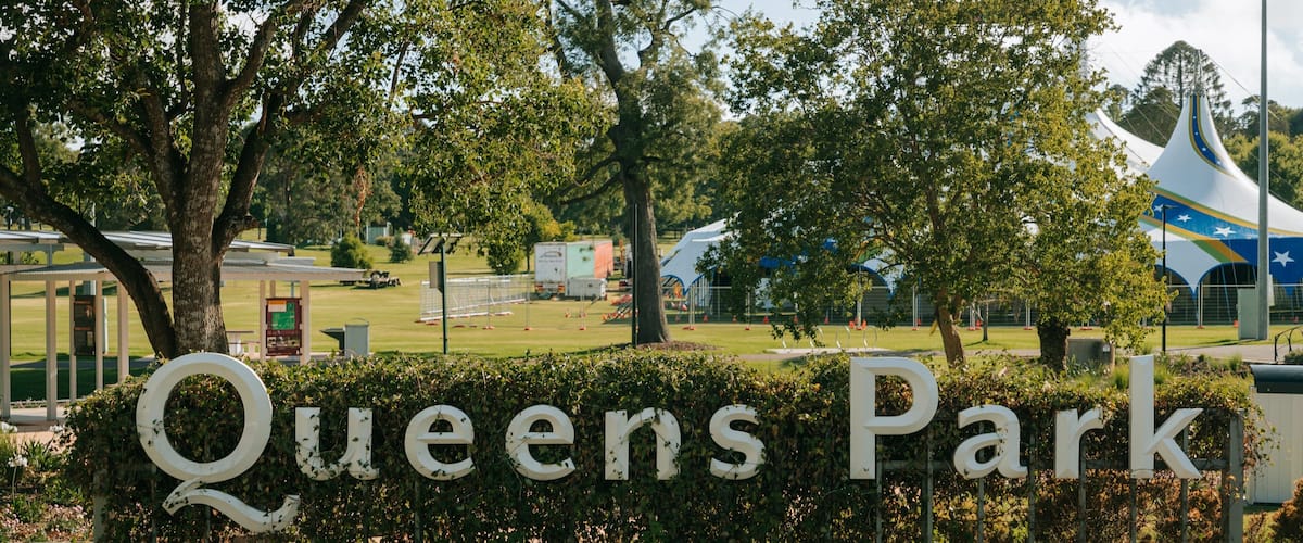 Queens Park featuring a garden and signage