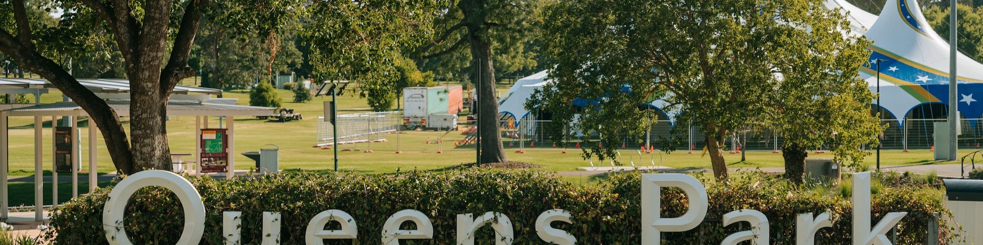 Queens Park featuring a garden and signage