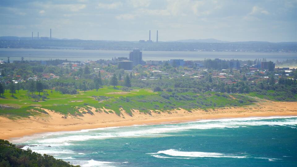 A coastal cityscape with a beach, industrial chimneys, and residential buildings.