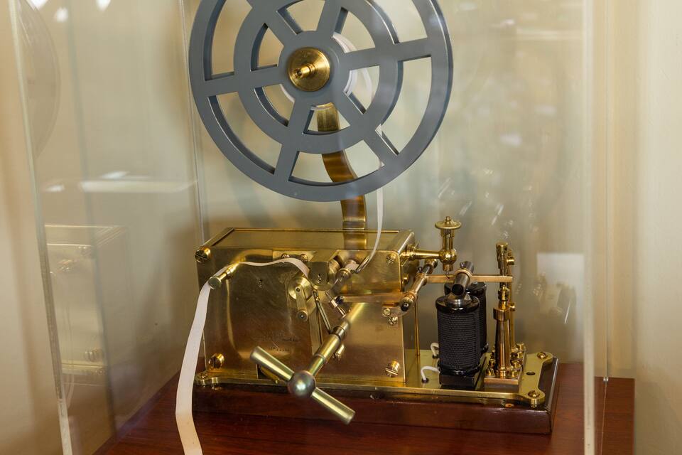 A brass mechanical device with a wheel and gears, likely a historical exhibit.