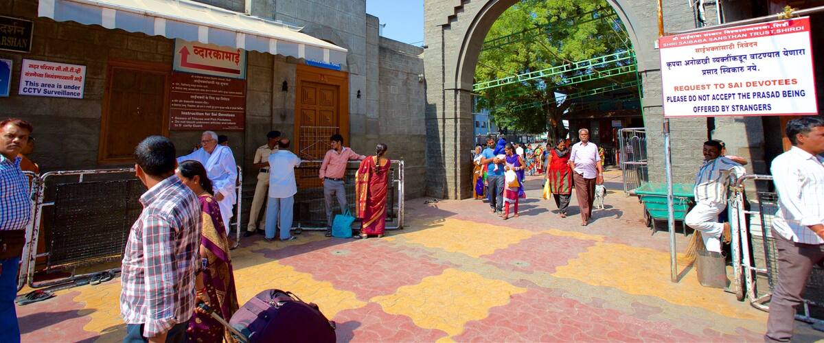 A busy entrance with people, a signboard, and a flag.