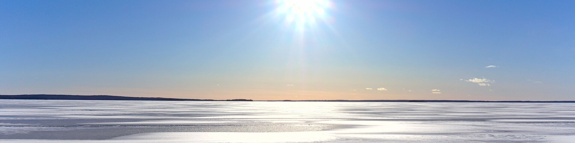Un paisaje helado y extenso con un sol brillante en el cielo.