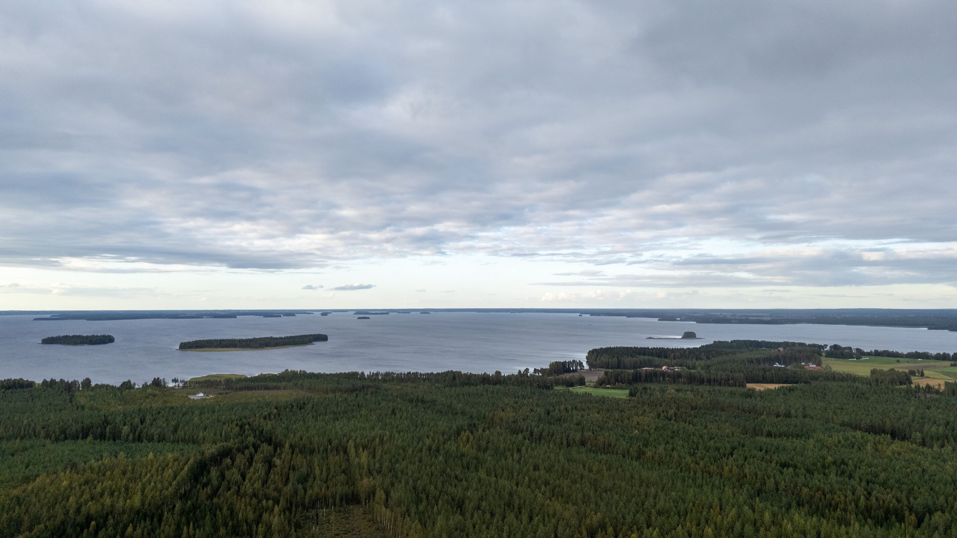 A coastal landscape with dense forests, a large body of water, and several small islands.