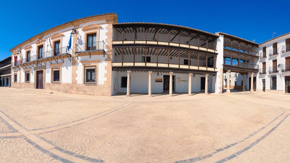 A historic plaza with a prominent circular building featuring balconies and columns, surrounded by traditional architecture.