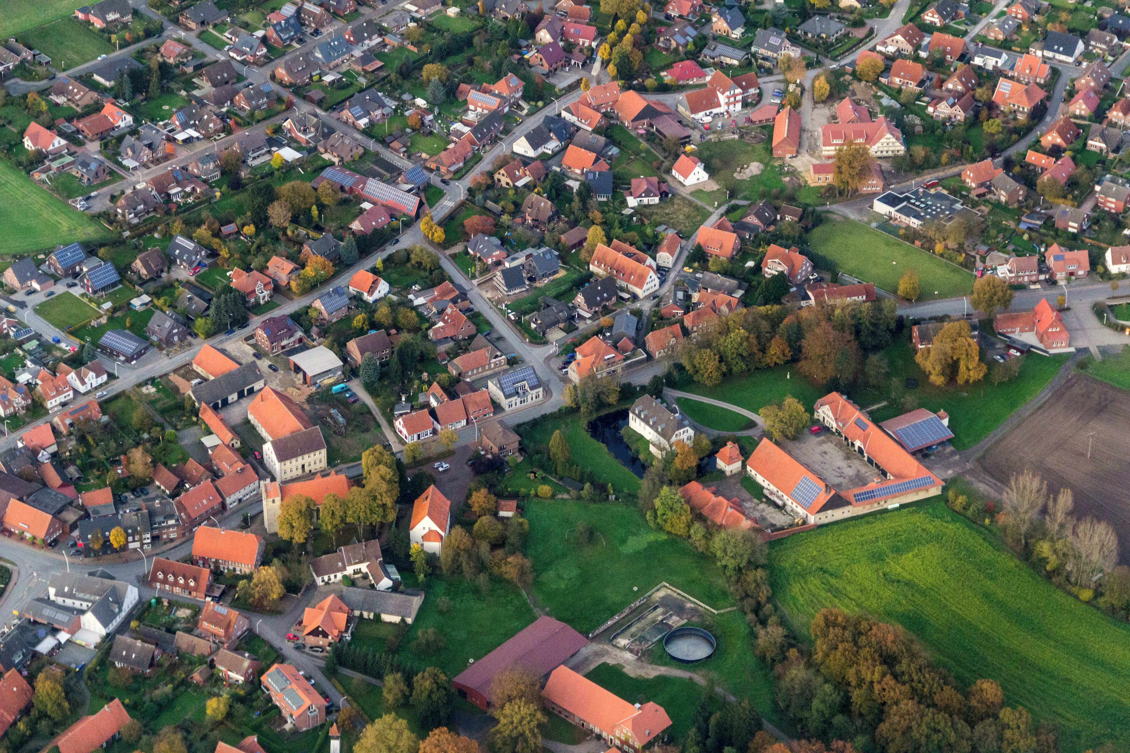An aerial view of a residential area with houses, roads, and green spaces.