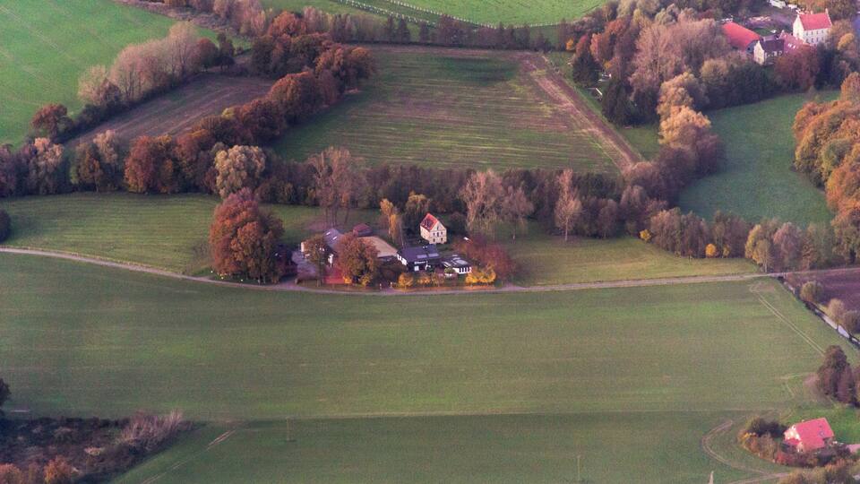 An aerial view of a rural landscape with fields, trees, and houses.