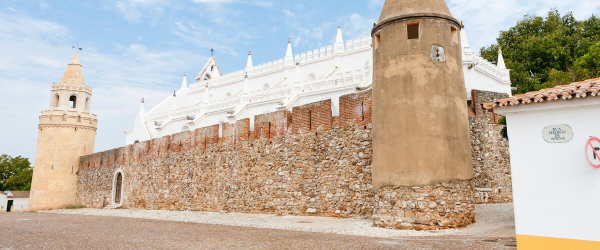 A historic fortress with white walls and a stone tower.