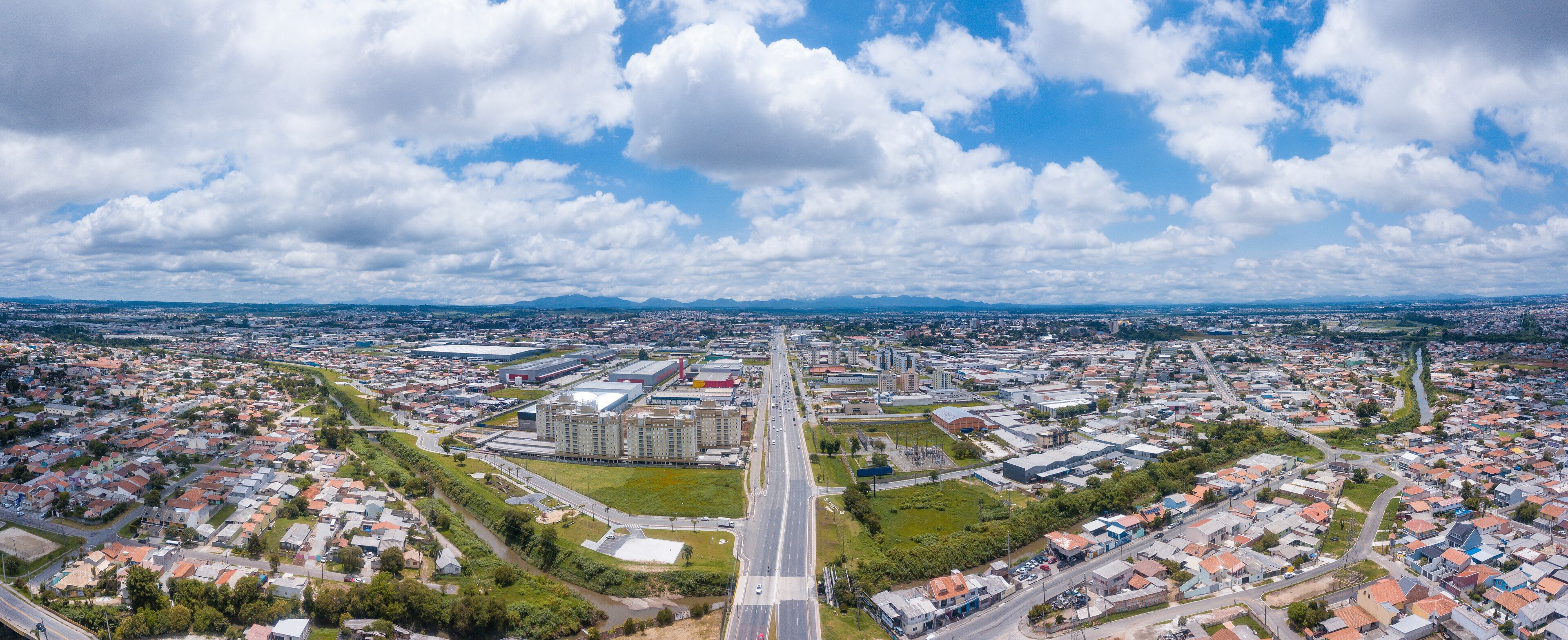 An aerial view of a city with a central highway, residential areas, and industrial buildings.