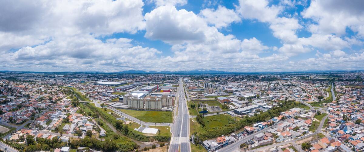 An aerial view of a city with a central highway, residential areas, and industrial buildings.