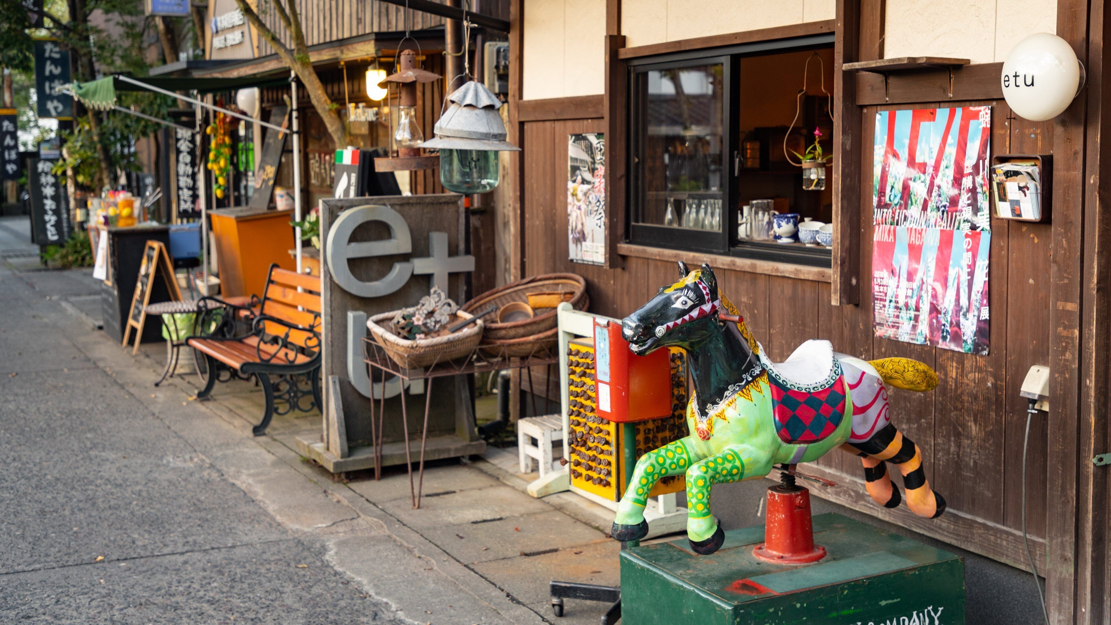 A colorful horse sculpture outside a shop with a sign that reads "e+".