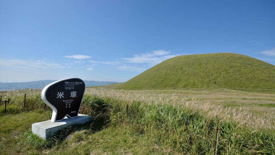 A grassy hill with a sign in the foreground.