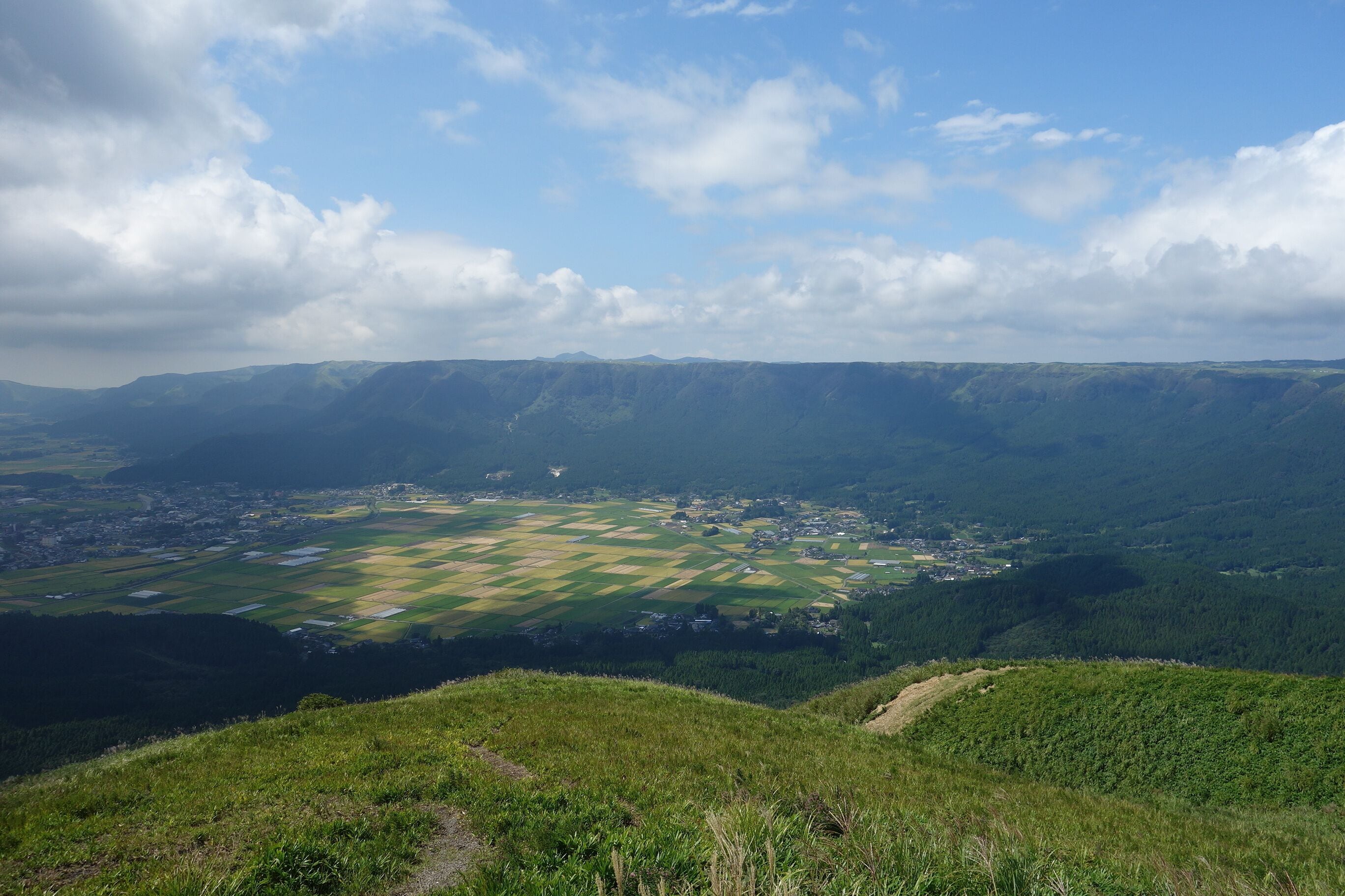A valley with fields, a town, and mountains in the background.