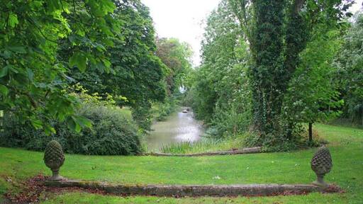 Gardens at Langar Hall. Typical of the Vale of Belvoir villages, Langar is built on a shallow ridge above the floor of the Vale. 54676, on the edge of the village, sits right on the edge of the ridge. The main landscaped gardens to the north drop steeply away from the drive and car-park towards a "ribbon" lake set out in a grid pattern, see the 1:25000 OS map. The stone wall with the pineapple finials is all that remains of an ornamental bridge which once crossed an extension of the lake, now filled in.
