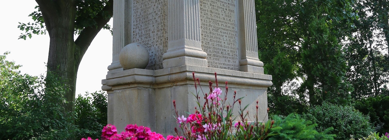 Ehrenmal (Kriegerdenkmal) im Bürgerpark neben dem Friedhof in Recke-Steinbeck, Kreis Steinfurt, Nordrhein-Westfalen, Deutschland. Hier der zentrale ältere Block des dreiteiligen Ensembles, auf dem die Namen der Steinbecker Gefallenen und Vermissten des Ersten Weltkriegs verzeichnet sind.