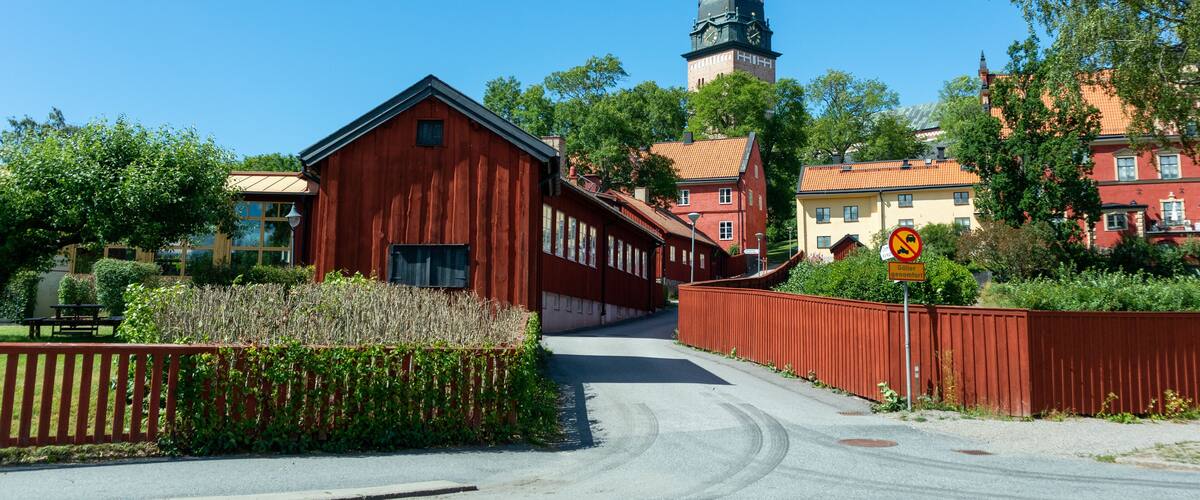 A red wooden building, a church with a dome, and a no parking sign.
