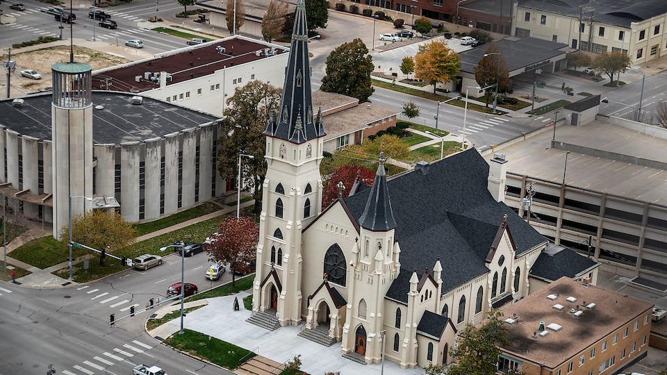 A church with a tall steeple and a parking garage in the background.