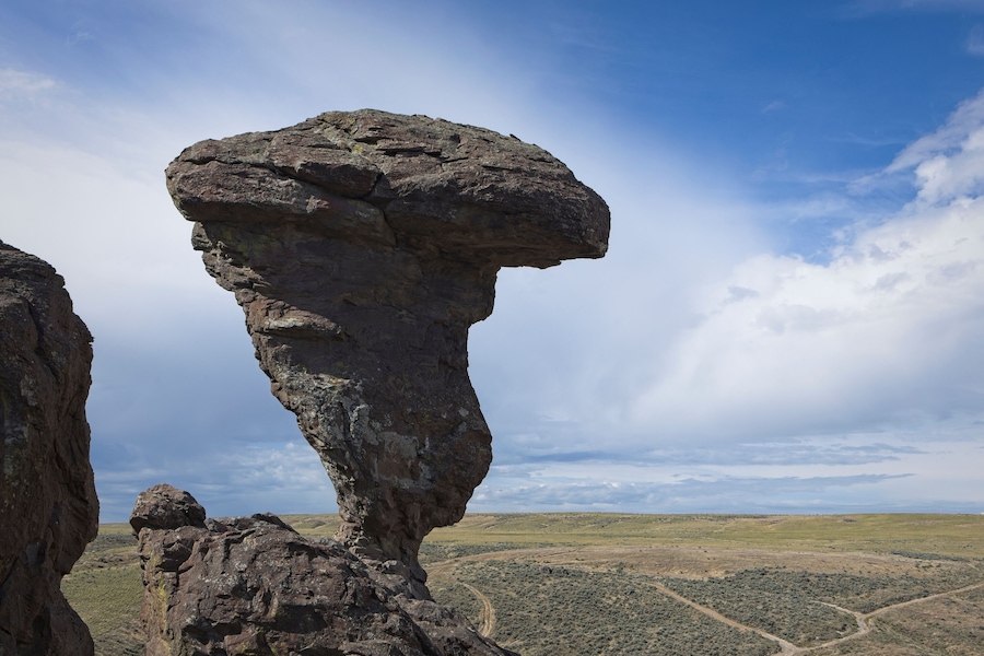 A rock formation with a prominent overhang in a desert landscape.