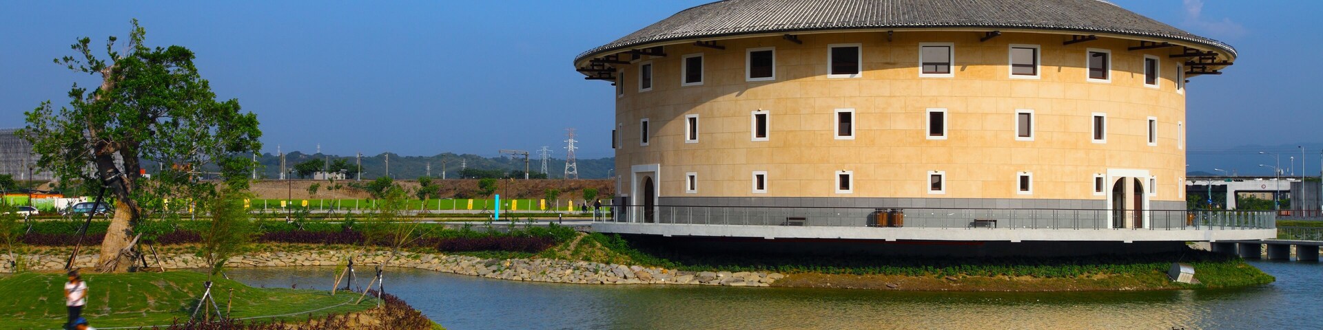 Un edificio circular junto a un río tranquilo, con patos.
