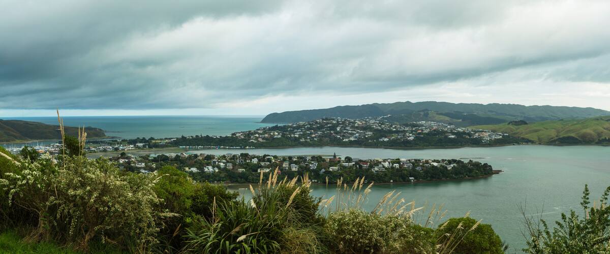 A coastal town with a bay, surrounded by hills and a cloudy sky.
