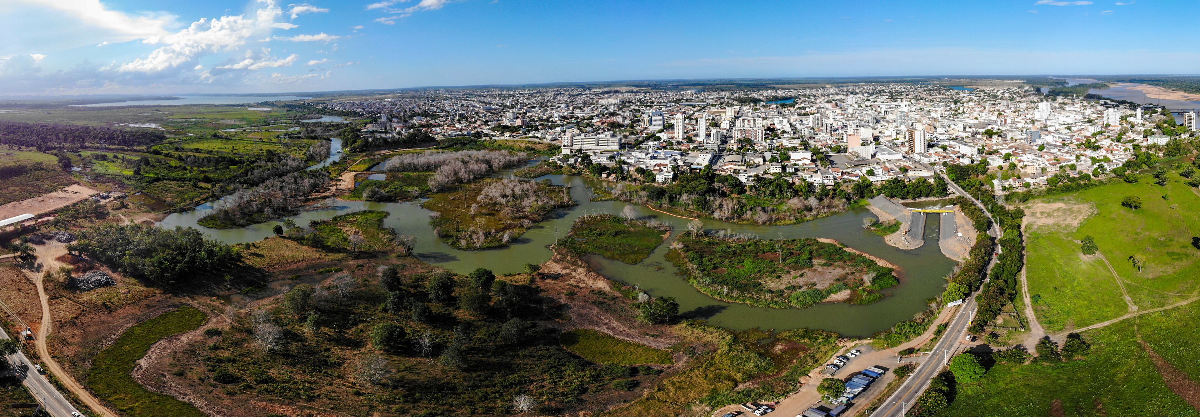 An aerial view of a city with a river and surrounding greenery.