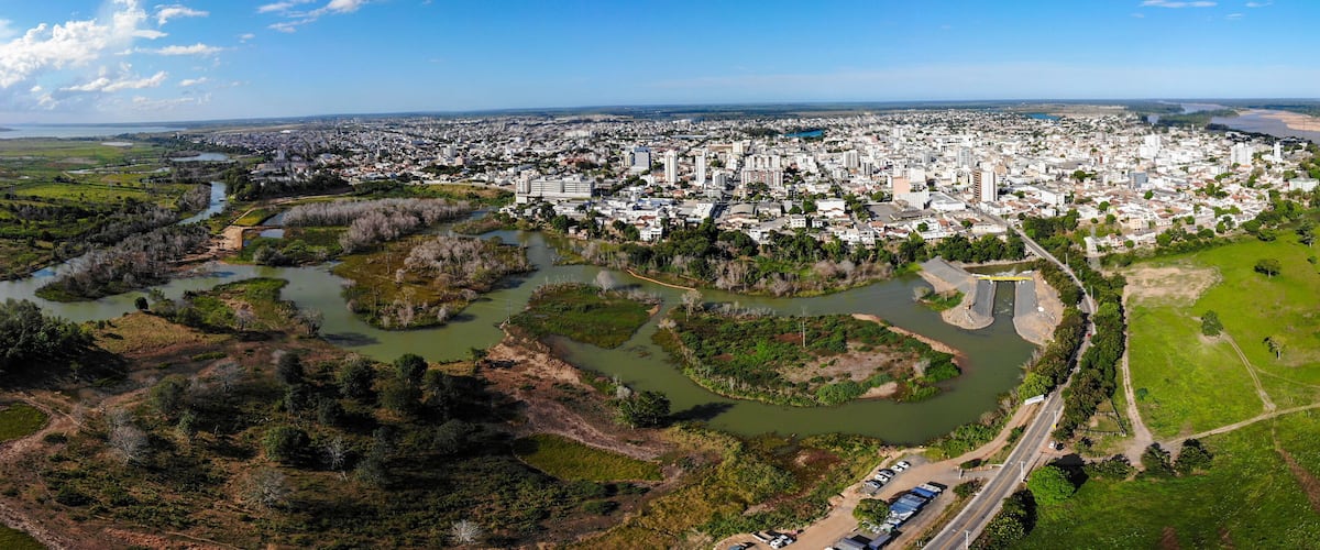 An aerial view of a city with a river and surrounding greenery.