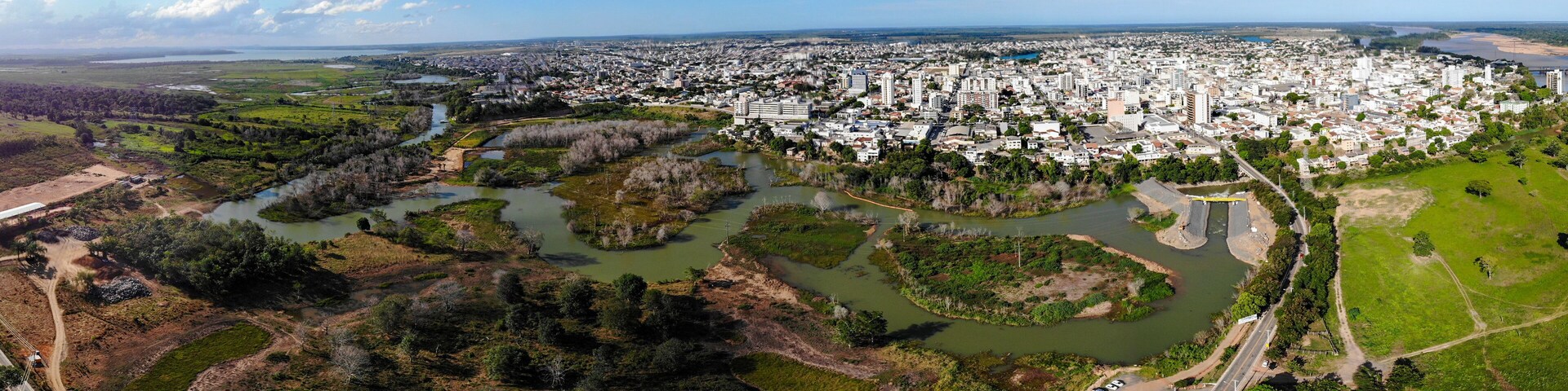 An aerial view of a city with a river and surrounding greenery.