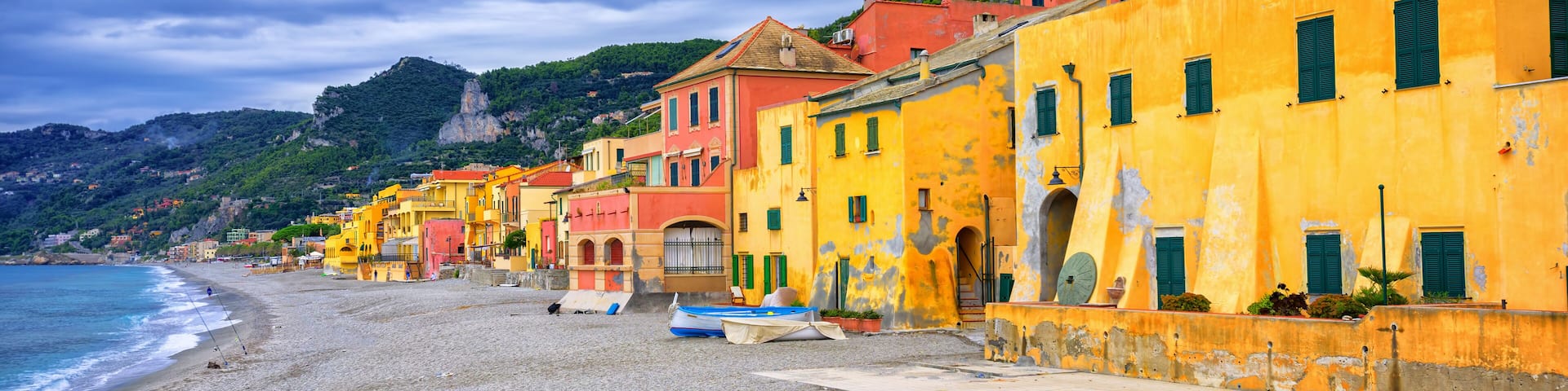 A coastal town with colorful buildings, a sandy beach, and a rocky hillside.