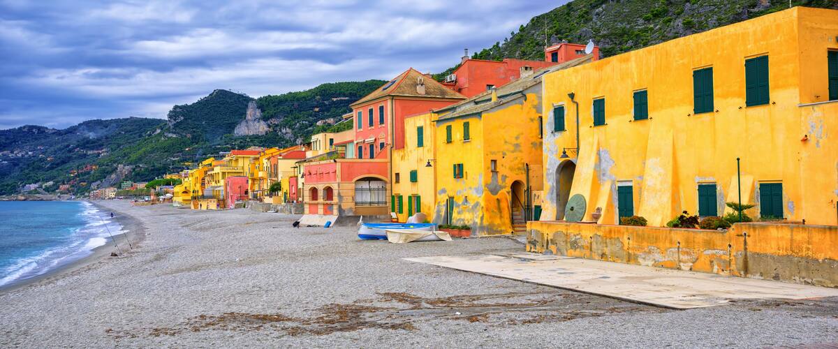 A coastal town with colorful buildings, a sandy beach, and a rocky hillside.